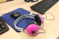 immagine con cuffie appoggiate su una scrivania, vicino ad un PC